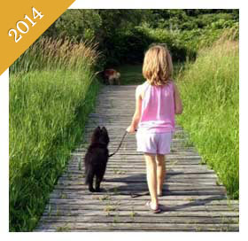 Same child walking a new puppy on boardwalk from 2014