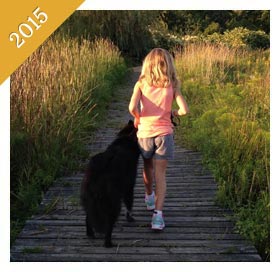 Same child walking same dog as an adult on boardwalk from 2015