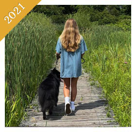 Same teenager is walking same dog on boardwalk from 2021